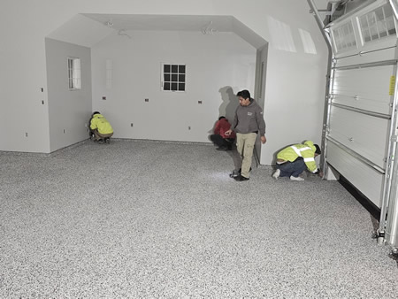 Polyaspartic topcoat being applied to a full broadcast flake garage floor